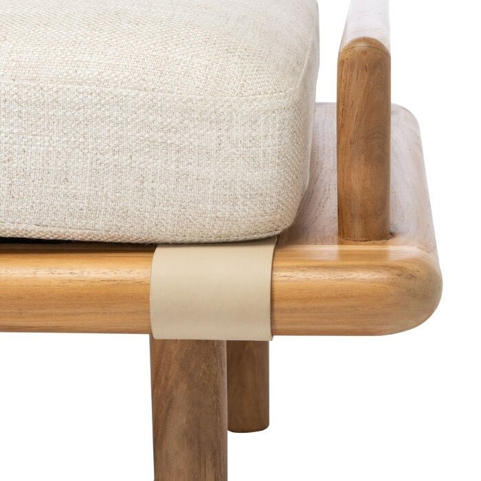 Close-up of a beige boucle upholstered cushion on a natural wood rounded bench frame, featuring a beige leather strap detail and a cylindrical wooden leg.