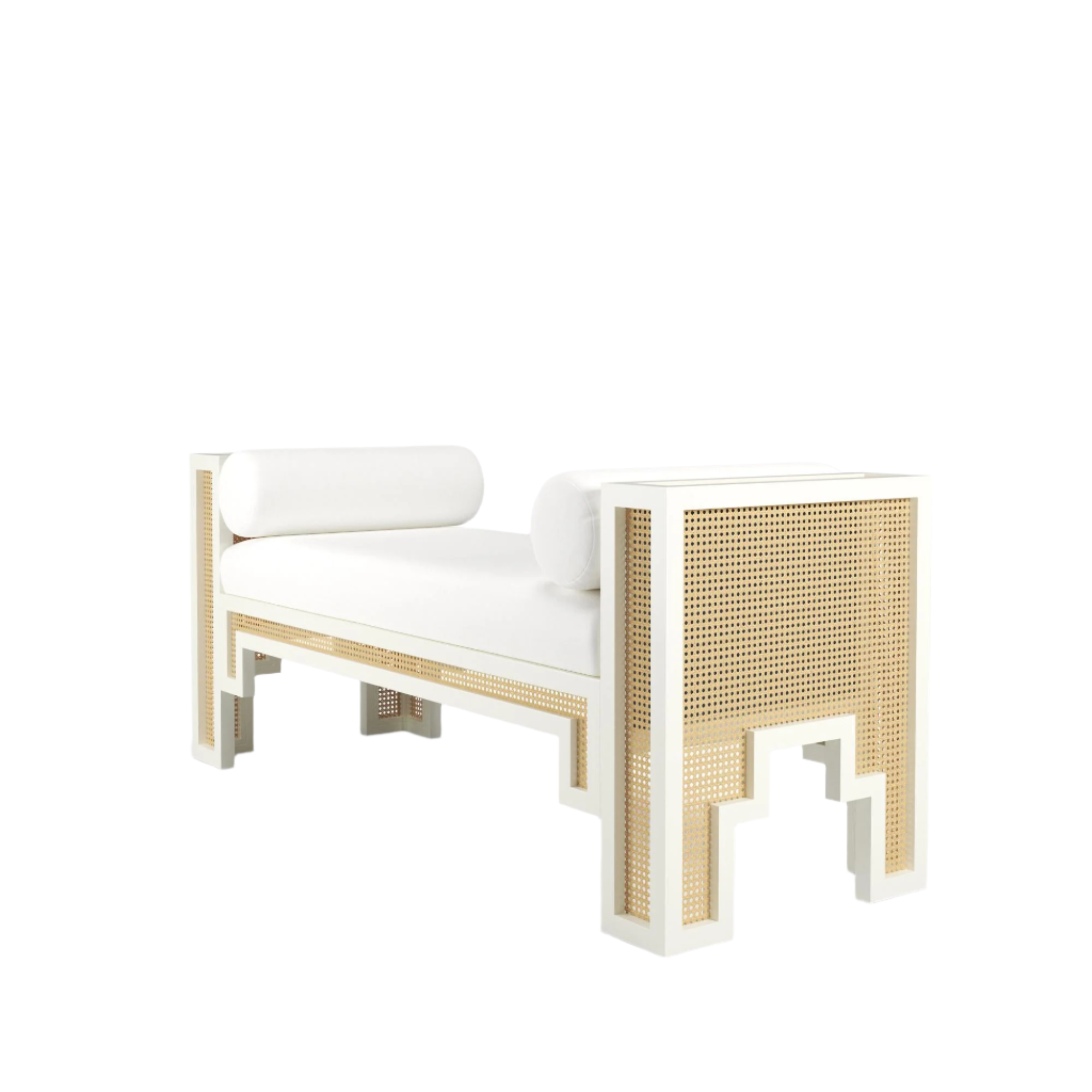 White upholstered end-of-bed bench with natural rattan cane panels set in a white solid wood frame, two cylindrical bolster pillows and geometric cutout legs in a boho-Scandinavian style.