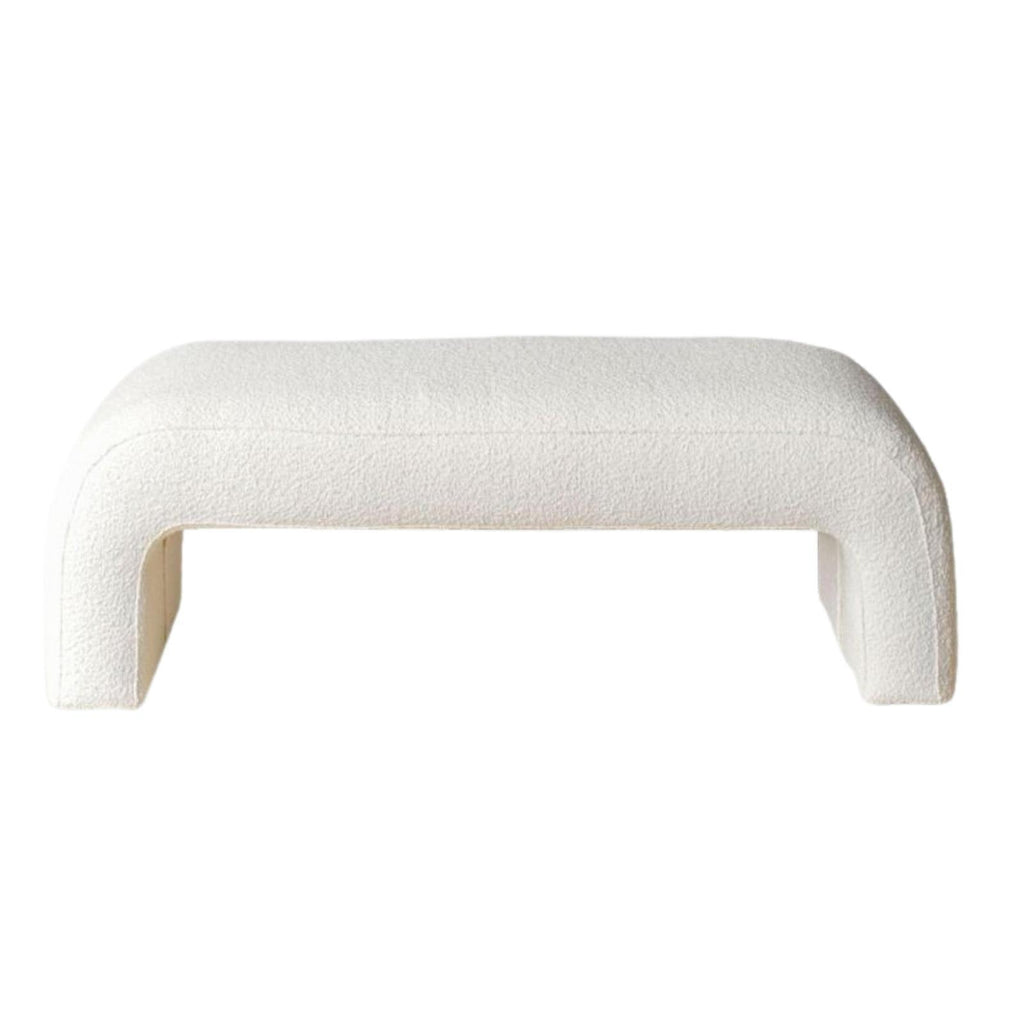 White boucle-upholstered end-of-bed bench with a low, armless silhouette, rounded corners and open U-shaped legs, shown against a white background.