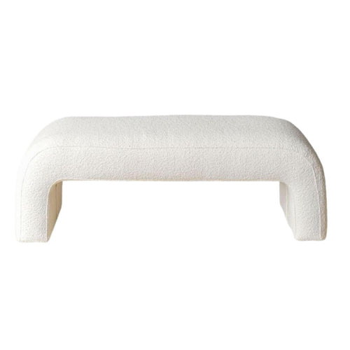 White boucle-upholstered end-of-bed bench with a low, armless silhouette, rounded corners and open U-shaped legs, shown against a white background.