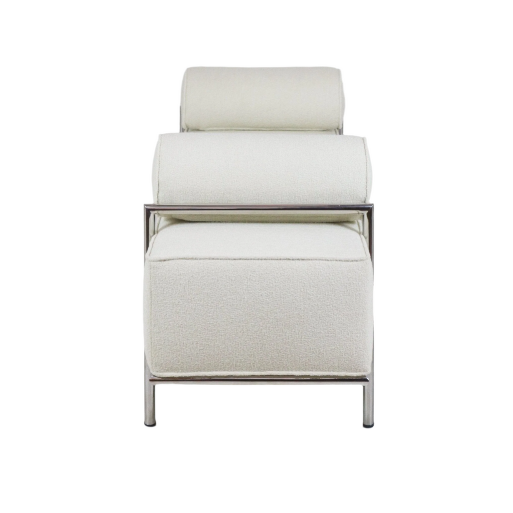 Front view of a modern end-of-bed bench upholstered in white boucle fabric with stacked cylindrical bolster cushions and a polished stainless-steel frame and legs.