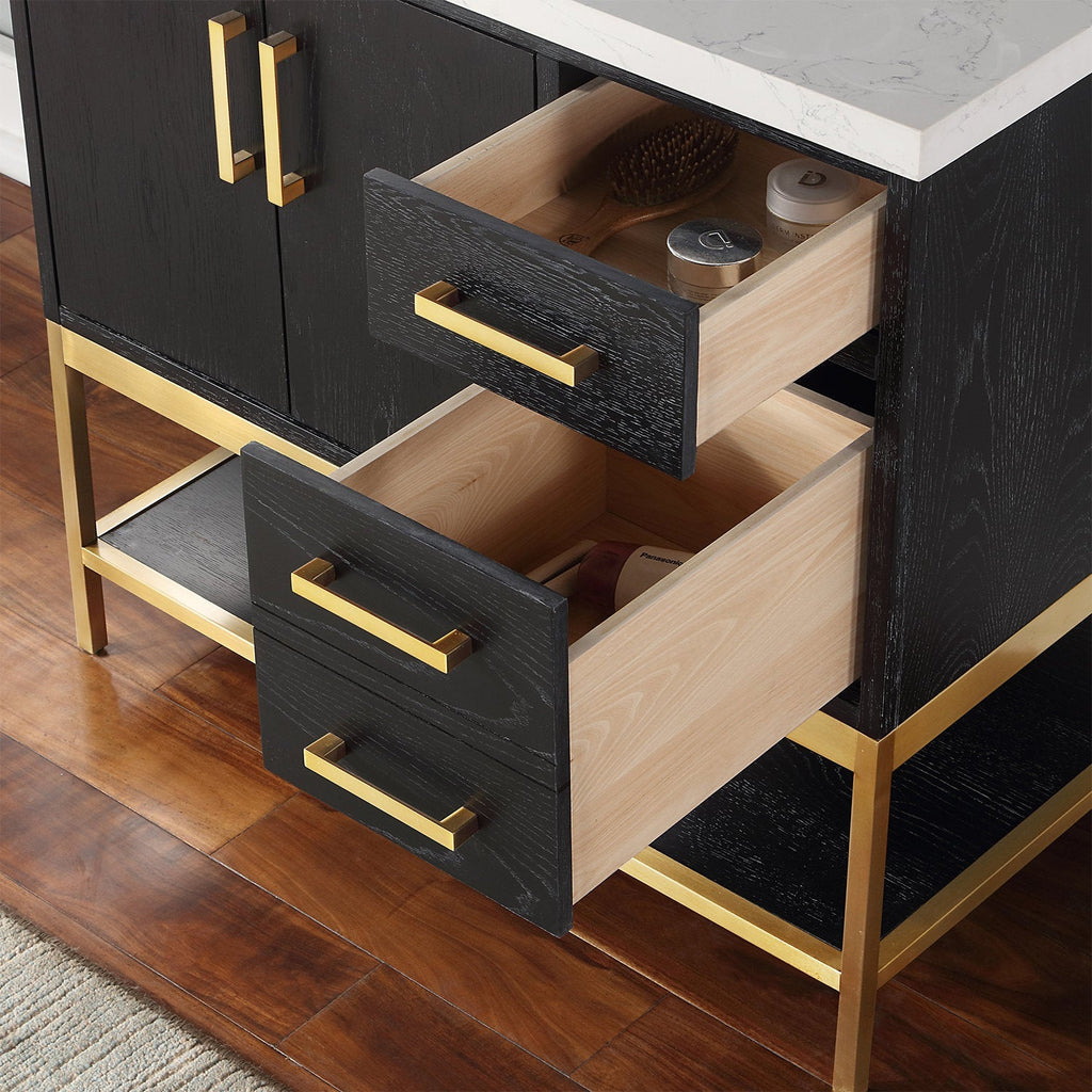 Close-up of a modern bathroom vanity with two open black-stained wood drawers showing light wood interiors, brass-tone rectangular handles and metal base, and a white stone countertop with toiletries inside the top drawer.