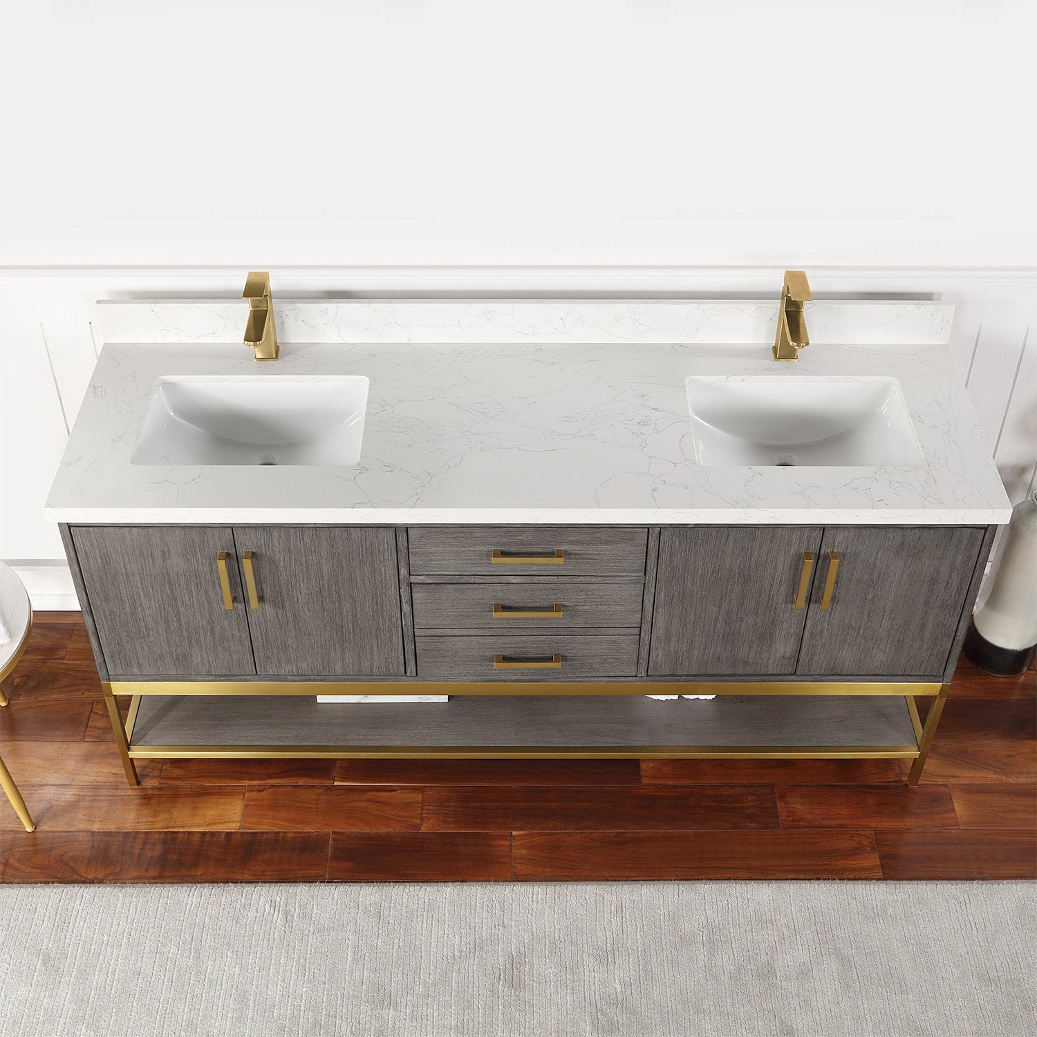 72-inch freestanding solid wood double-sink bathroom vanity with white stone-look countertop and integrated rectangular ceramic sinks, gray wood finish, brass-gold faucets and handles, and open lower shelf for storage.
