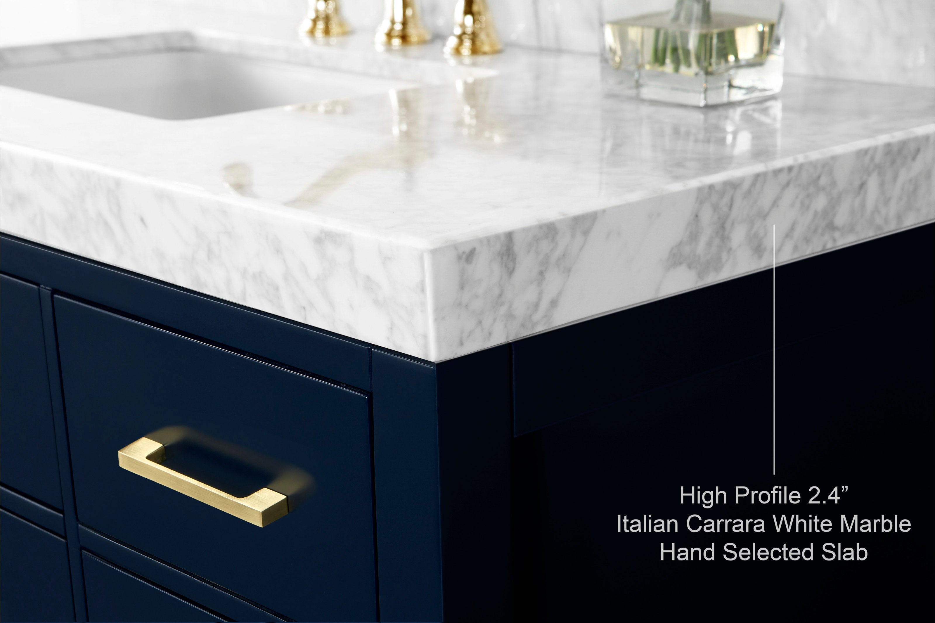 Close-up of a high-profile 2.4-inch Italian Carrara white marble countertop with undermount sink, resting on a deep navy solid-wood vanity featuring a brushed brass drawer pull.