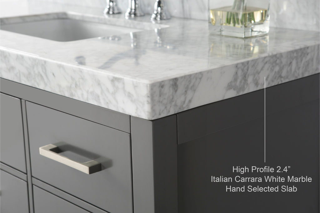 Close-up of a corner of a modern stone-colored single-sink vanity with a 2.4" high-profile Italian Carrara white marble countertop, undermount sink edge and a brushed metal drawer pull.