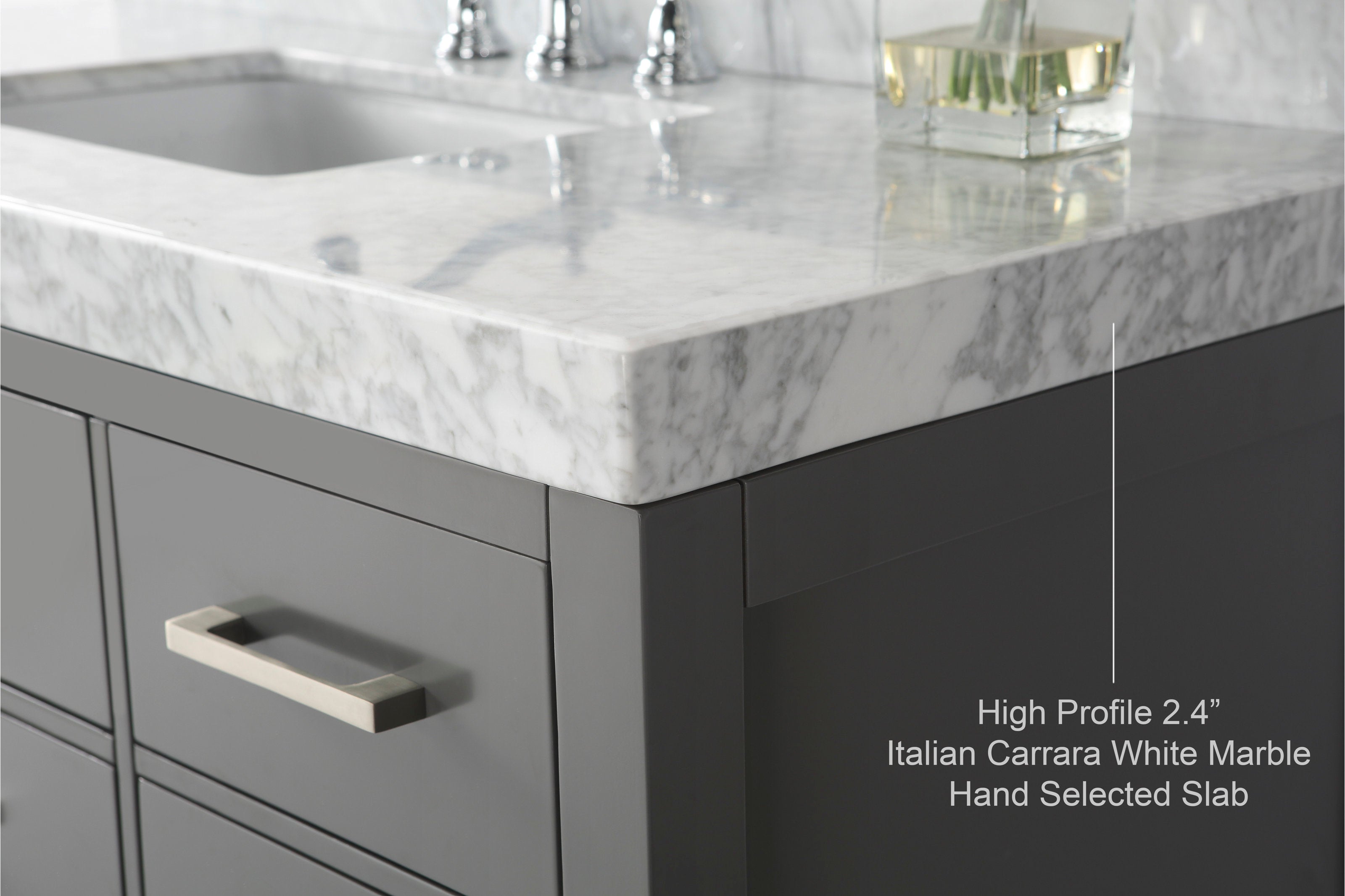 Close-up of a corner of a modern stone-colored single-sink vanity with a 2.4" high-profile Italian Carrara white marble countertop, undermount sink edge and a brushed metal drawer pull.