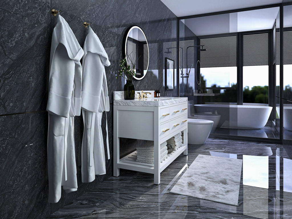 Modern white 48-inch single-sink vanity with marble countertop and brass drawer pulls on a solid wood frame, open towel shelf beneath; round mirror, dark stone marble walls, freestanding tub and glass shower visible.