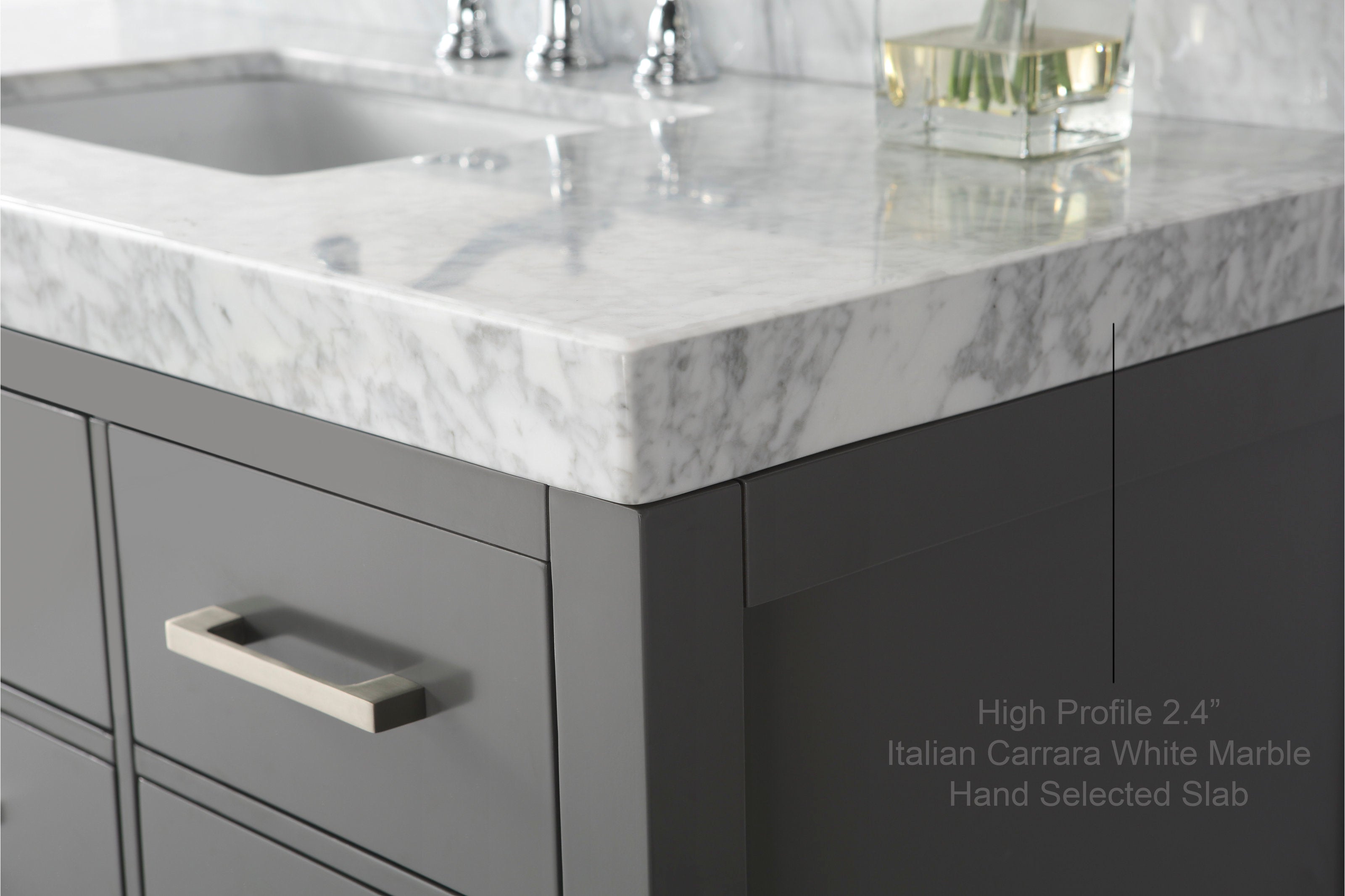 Close-up of a 2.4-inch Italian Carrara white marble countertop on a stone-colored solid wood modern vanity, showing the corner, undermount sink edge, chrome faucet reflection and brushed nickel rectangular drawer handle.
