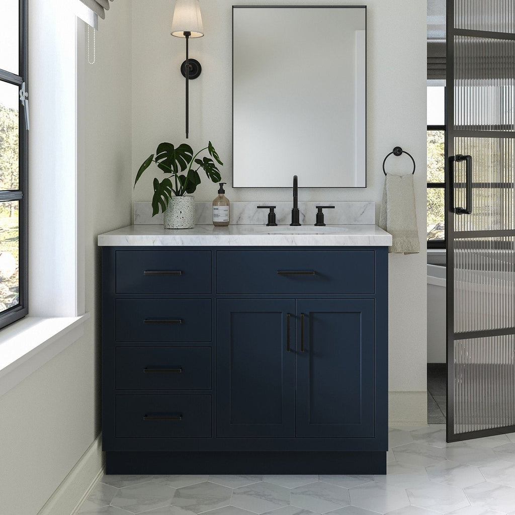 Modern 43-inch solid wood single-sink bathroom vanity with a stone marble top, deep navy painted base, matte black faucet and hardware, soft-close drawers and cabinet, mirror and potted plant on the countertop.