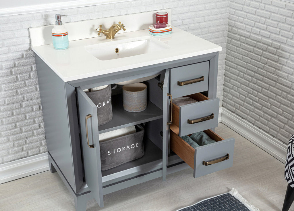 Modern gray solid-wood bathroom vanity with a white stone countertop and integrated ceramic sink, antique brass faucet and hardware; two open cabinet doors and three partially open drawers revealing wood interiors and fabric storage bins.