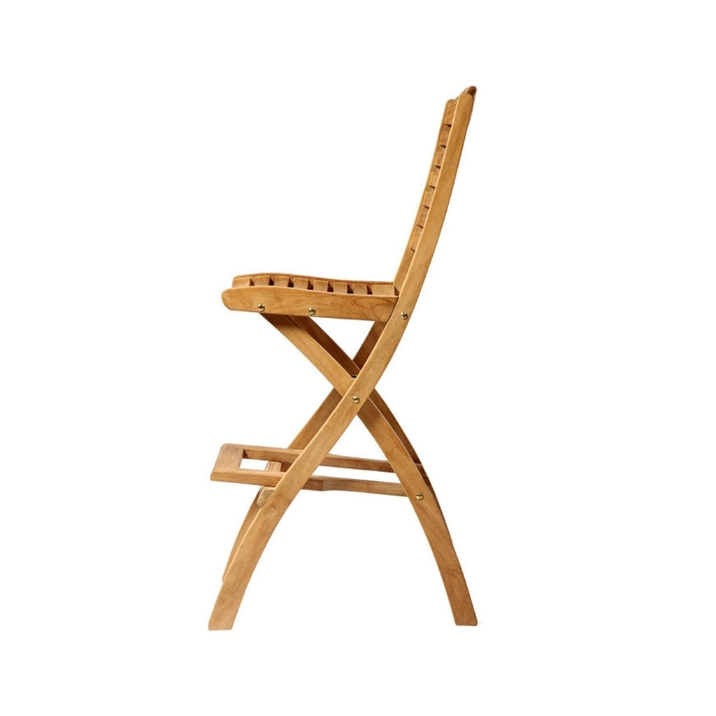 Side view of a natural teak folding armless outdoor bar stool with slatted seat and back, X-frame legs, brass pivot hardware and integrated footrest in a warm coastal teak finish.