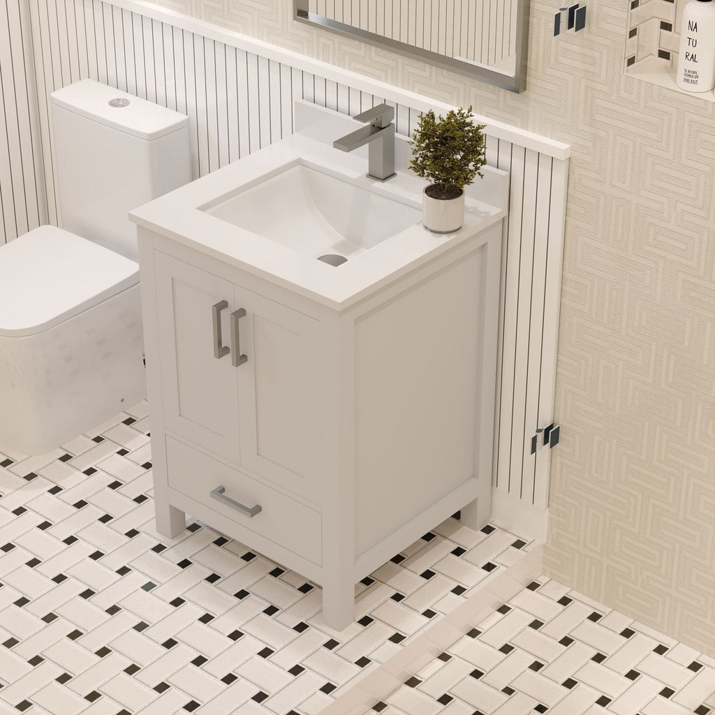 Stone-colored 24-inch solid wood freestanding bathroom vanity with integrated white ceramic sink, rectangular modern faucet and brushed metal handles, a small potted plant on top, shown beside a toilet on patterned tile floor.