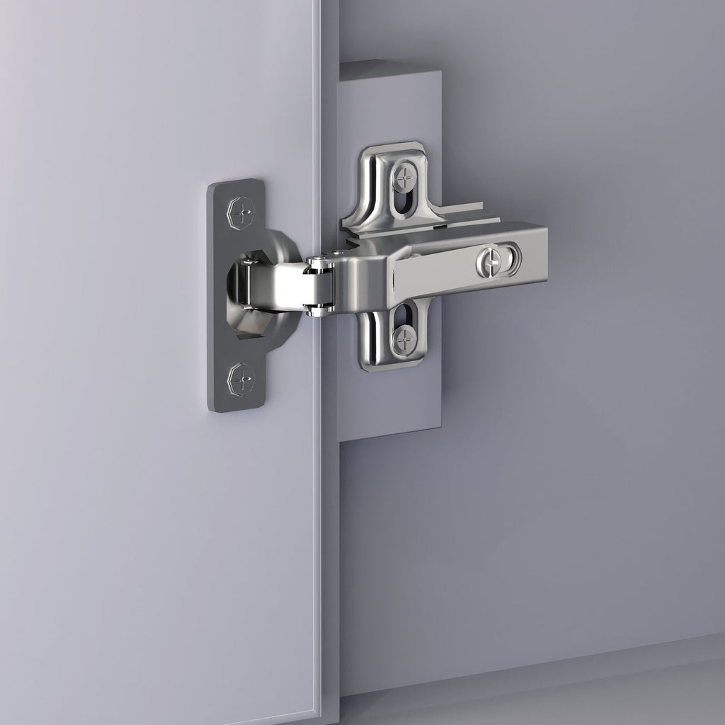 Close-up of a polished chrome soft-close cabinet hinge mounted on a stone-colored solid wood vanity door and frame, showing the arm, mounting plate and adjustment screws.