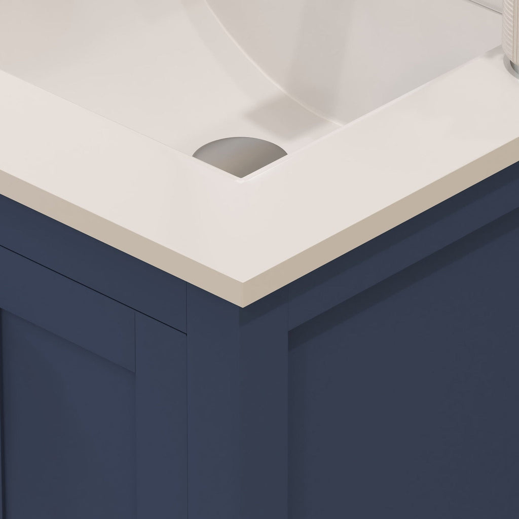 Close-up of a modern 24-inch bathroom vanity corner showing a stone-colored countertop with an integrated ceramic sink resting on a navy-painted solid wood cabinet.