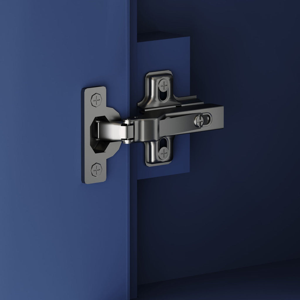 Close-up of a polished metal soft-close cabinet hinge mounted to a modern solid wood vanity door, showing screw heads and the mounting plate against a deep blue background.