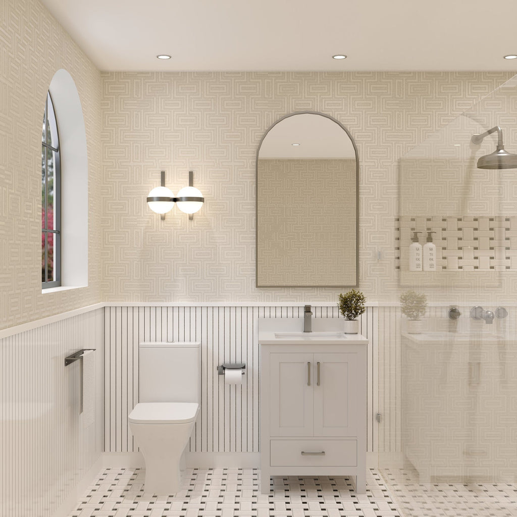 Freestanding 24-inch stone-colored solid wood bathroom vanity with ceramic sink and stone top, single matte metal faucet, arched mirror and globe wall sconce above; toilet to left and glass shower to right.