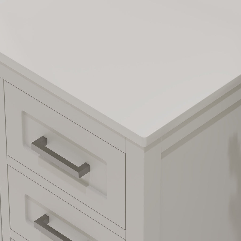 Close-up of a stone-colored solid wood bathroom vanity corner showing a smooth stone top with a rounded edge, inset drawer fronts and rectangular brushed metal handles in a modern contemporary style.