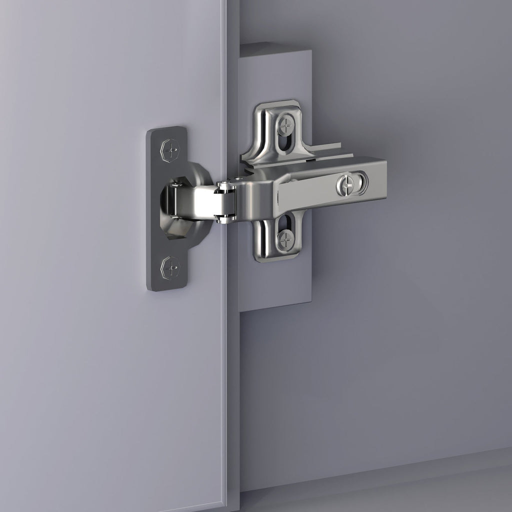 Close-up of a polished chrome European-style cabinet hinge mounted on a stone-colored solid wood vanity door and jamb, showing the screw plates and pivot mechanism.