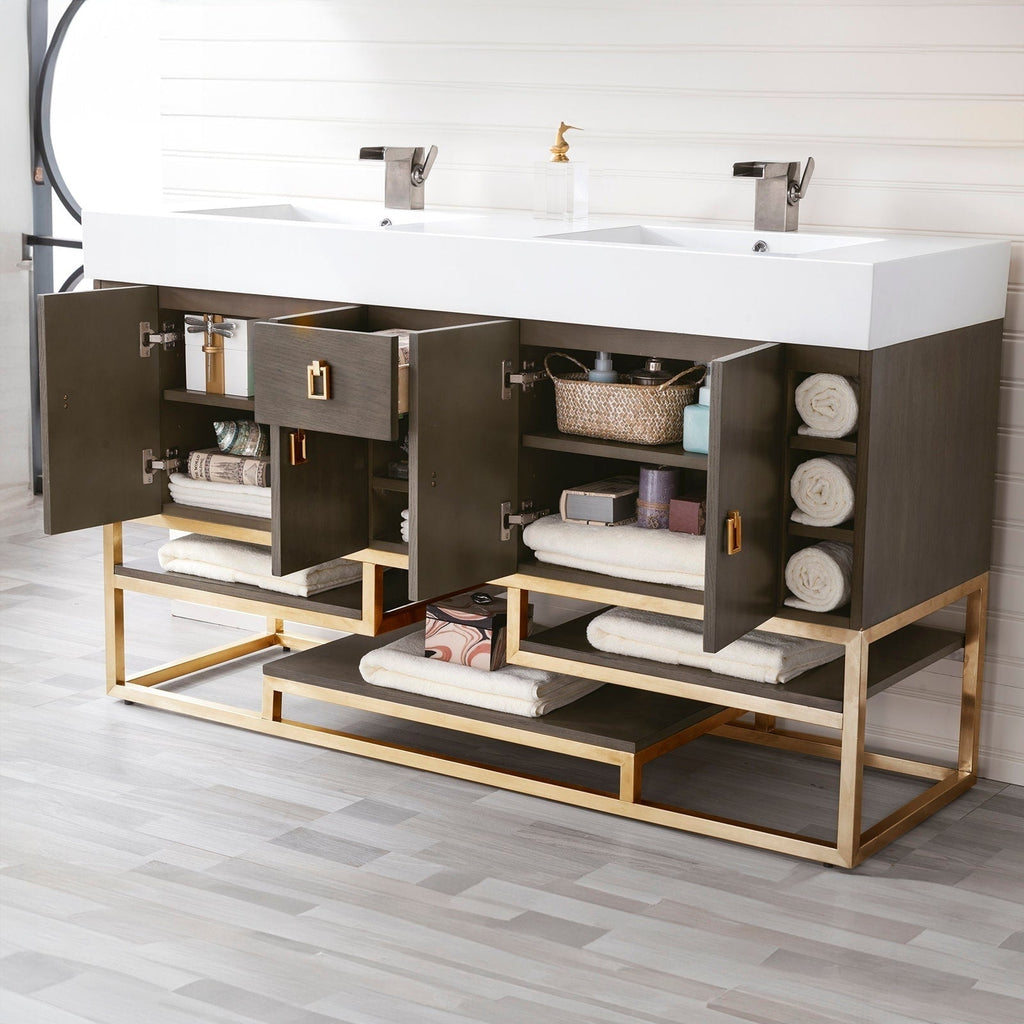 Modern solid-wood bathroom vanity with a white glossy stone composite double-sink top, dark wood cabinet and gold-finish metal base, open shelves and cabinets staged with rolled towels, basket and two metal faucets.