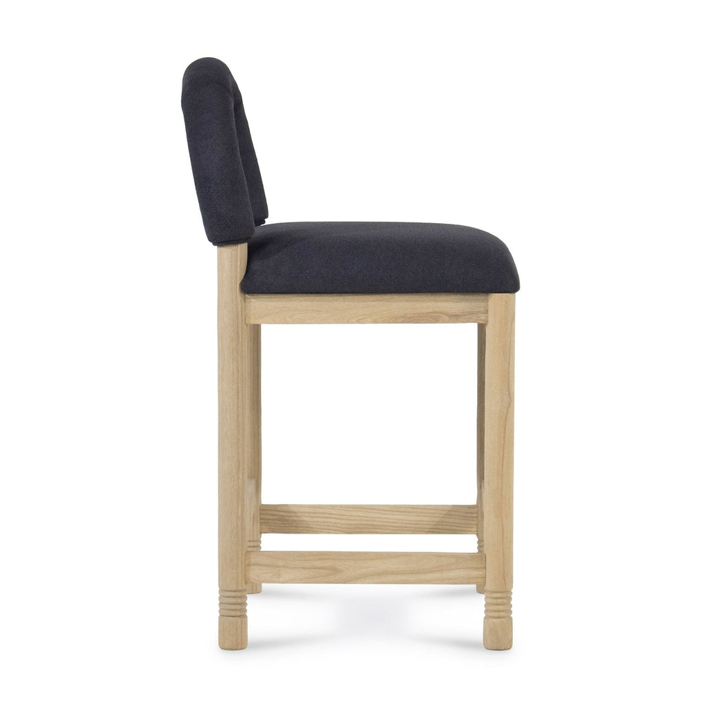 Side profile of a counter stool with a natural oak frame and charcoal bouclé fabric seat and low back, showing square legs, rectangular stretchers and subtle turned detailing at the feet.