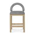 Front view of a counter stool with a light oak frame and cushioned gray bouclé seat and rounded upholstered back, featuring square legs and double horizontal foot rails.