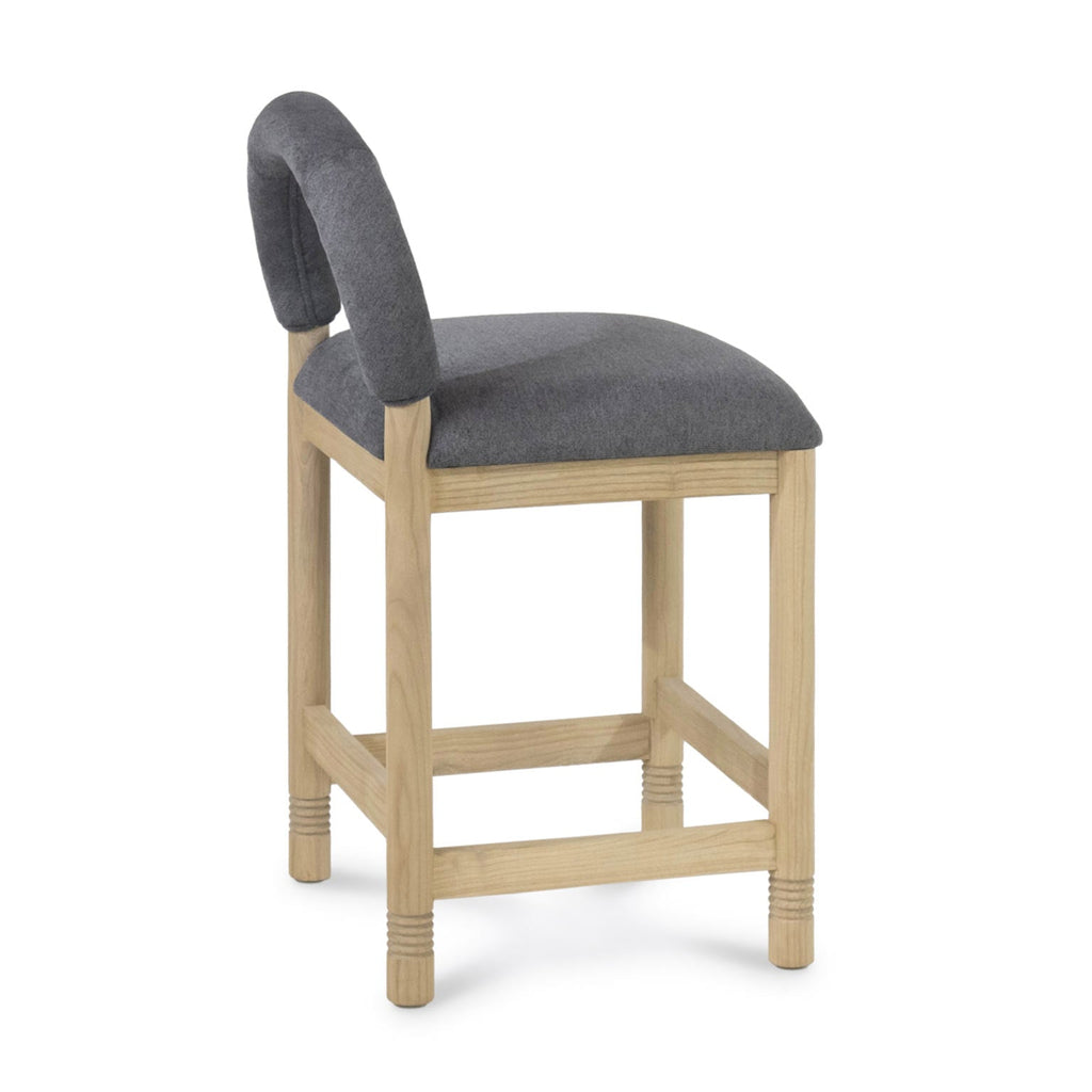 Side view of a counter-height stool with a natural oak frame and cushioned gray bouclé seat and low rounded backrest.