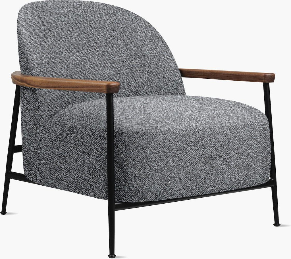 Contemporary accent chair upholstered in gray boucle fabric with a rounded back, thick cushioned seat, walnut-finished wooden armrests and slim black metal legs and frame.
