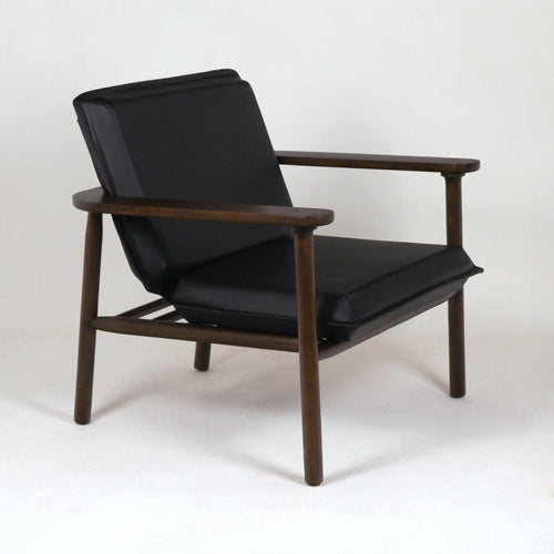 Midcentury-style lounge chair with black faux leather seat and angled cushioned back set in a warm brown solid wood frame with rounded arms and tapered legs.