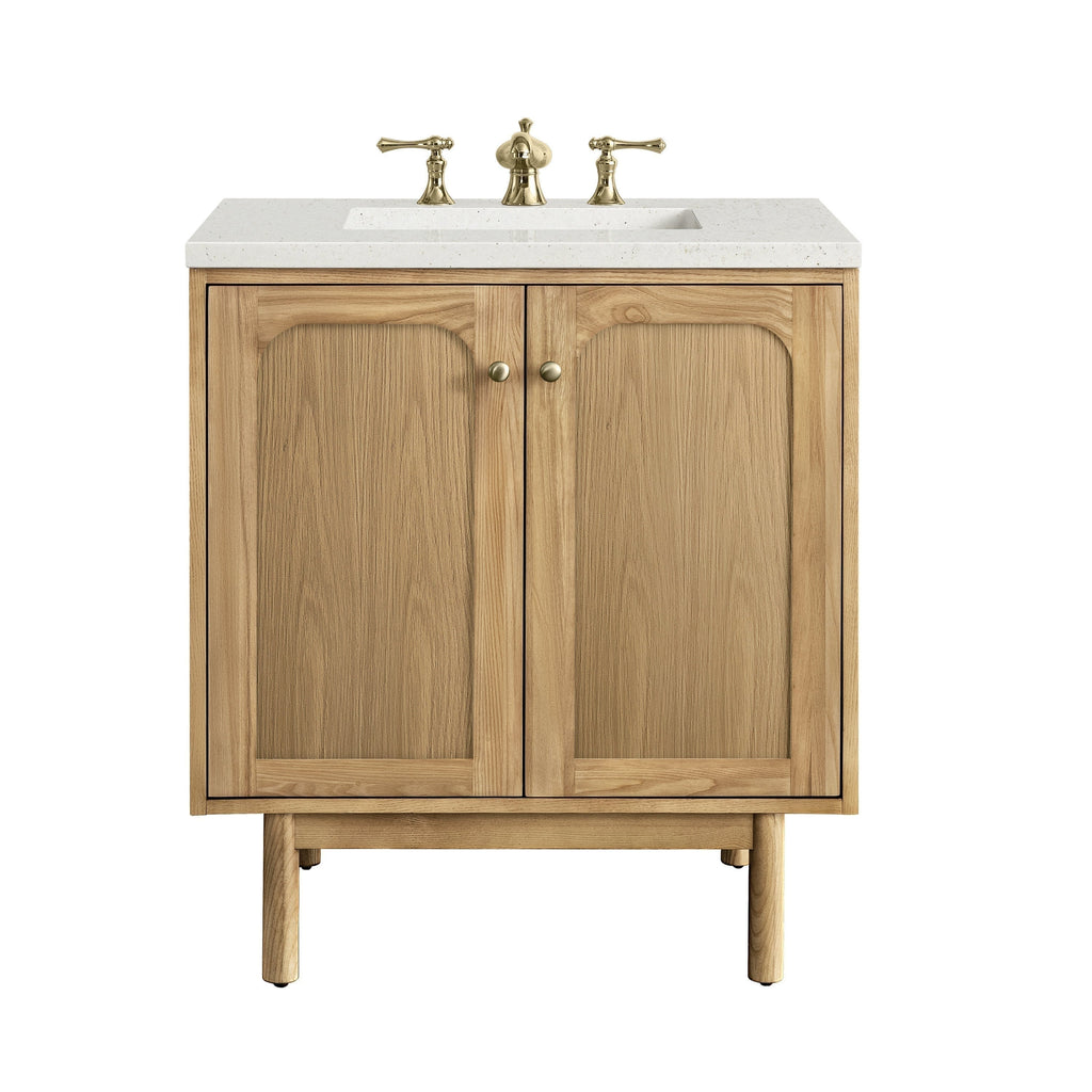 30-inch freestanding natural wood bathroom vanity with a light stone quartz top, rectangular undermount sink, three-piece brass widespread faucet, two paneled cabinet doors with round brass knobs and tapered legs.