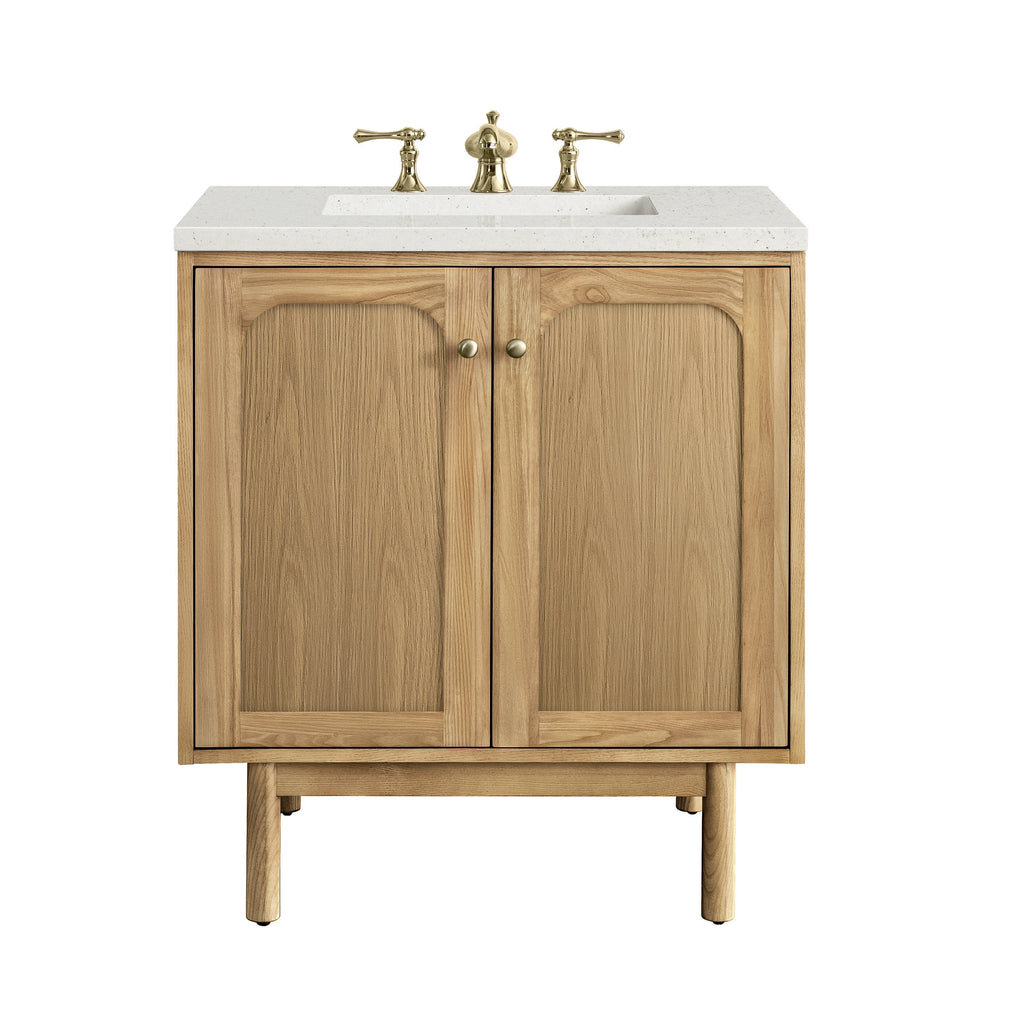 30-inch freestanding natural wood bathroom vanity with a light stone quartz top, rectangular undermount sink, three-piece brass widespread faucet, two paneled cabinet doors with round brass knobs and tapered legs.