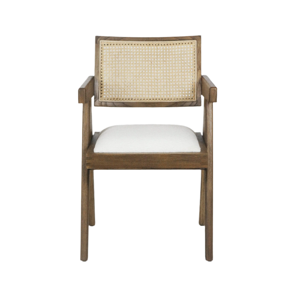 Front view of a mid-century modern dining chair with a natural wood frame, woven cane backrest, slim wooden arms and a white upholstered seat cushion.
