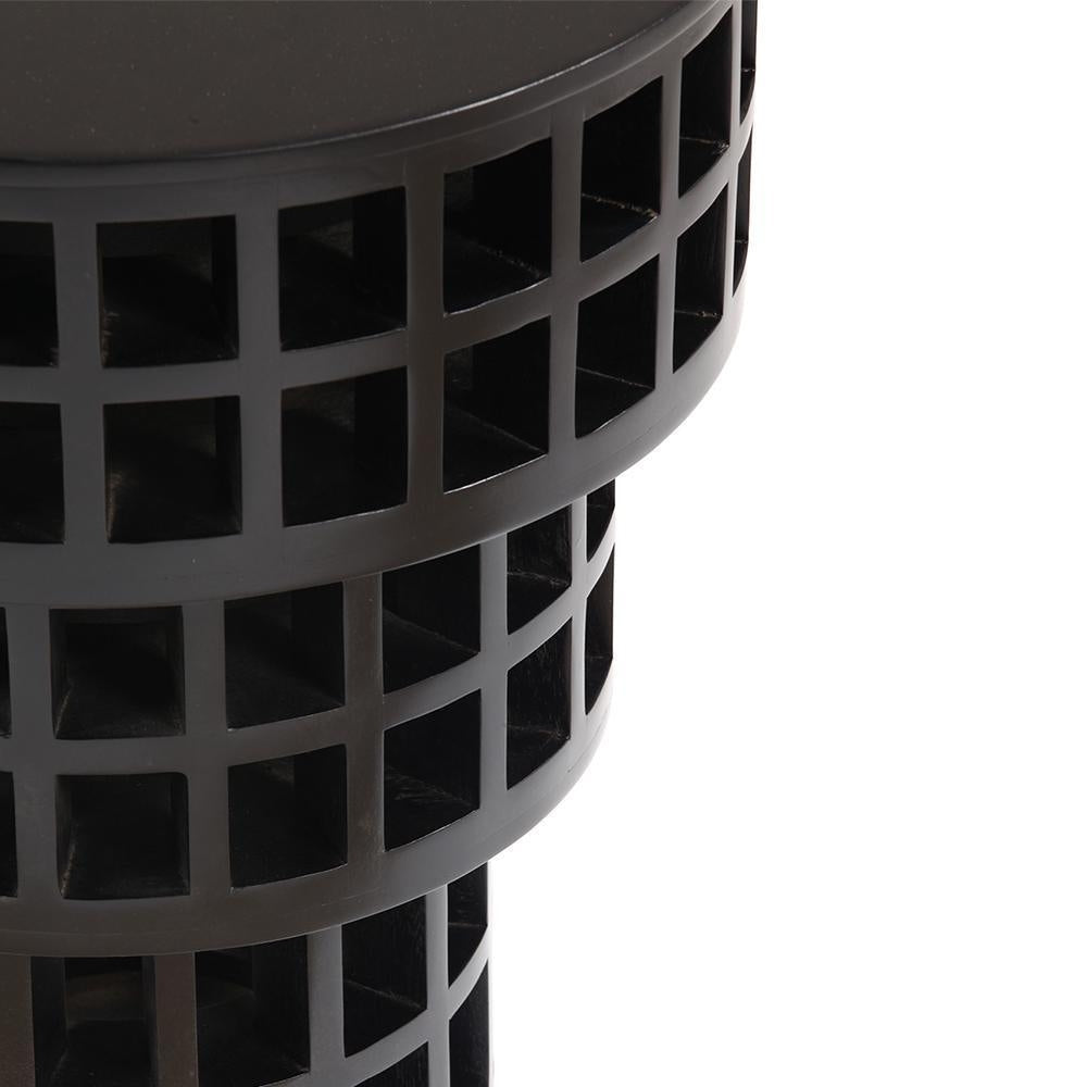 Close-up of a solid wood black mahogany side table showing stacked cylindrical tiers with square lattice cutouts and a smooth round top.