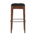Front-facing backless counter stool with a walnut-finished wood frame, black tufted leather seat cushion and brushed metal footrest/stretcher on a white background.