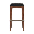 Front-facing backless counter stool with a walnut-finished wood frame, black tufted leather seat cushion and brushed metal footrest/stretcher on a white background.