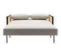 Front view of a modern beige upholstered sofa bed with black metal legs, wooden arms featuring cane panels, and two rounded back cushions, shown in the flattened bed position on a white background.
