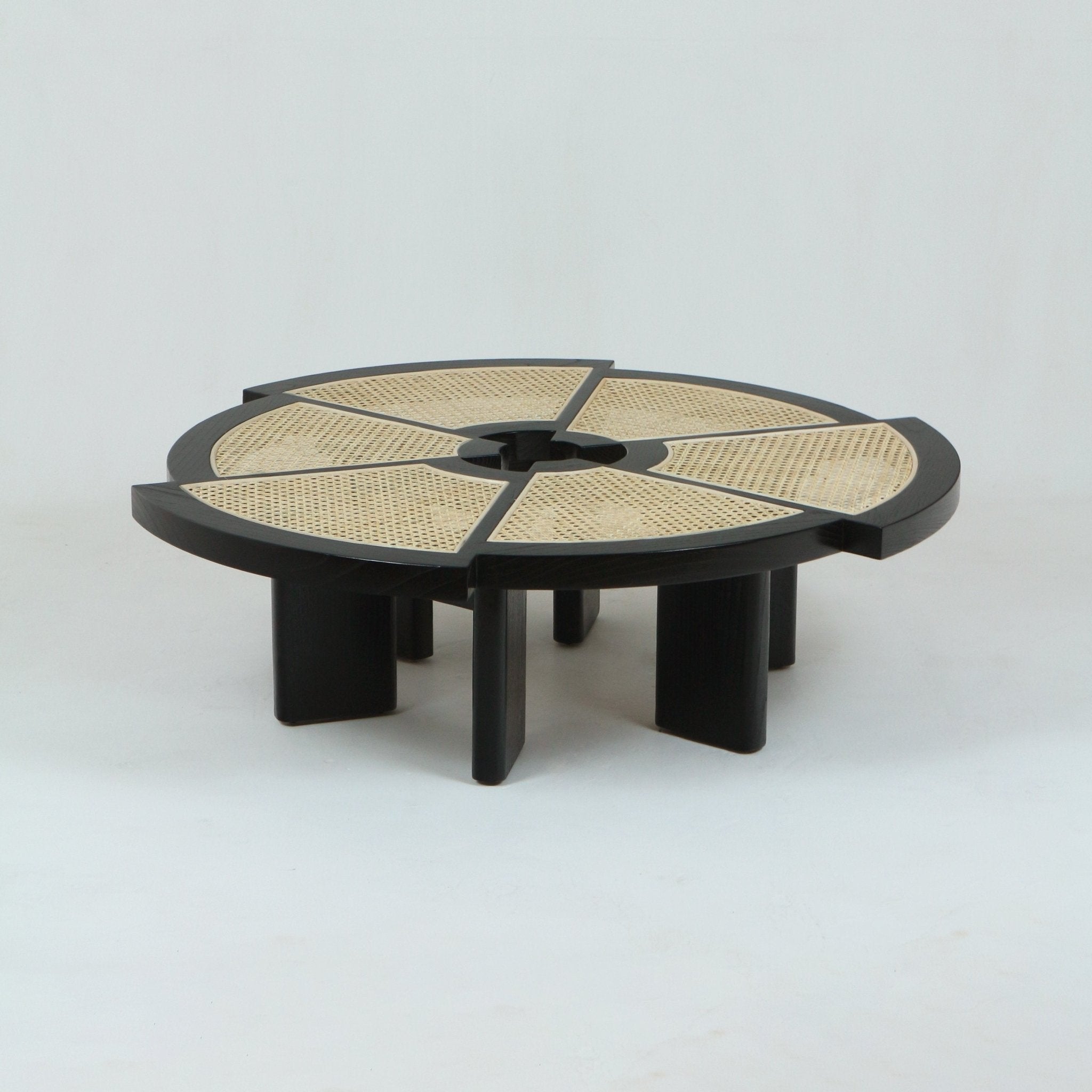 Low round modern coffee table with a black stained solid-wood frame and six natural cane-woven wedge panels in the tabletop, featuring a central circular cutout and short rectangular slab legs.