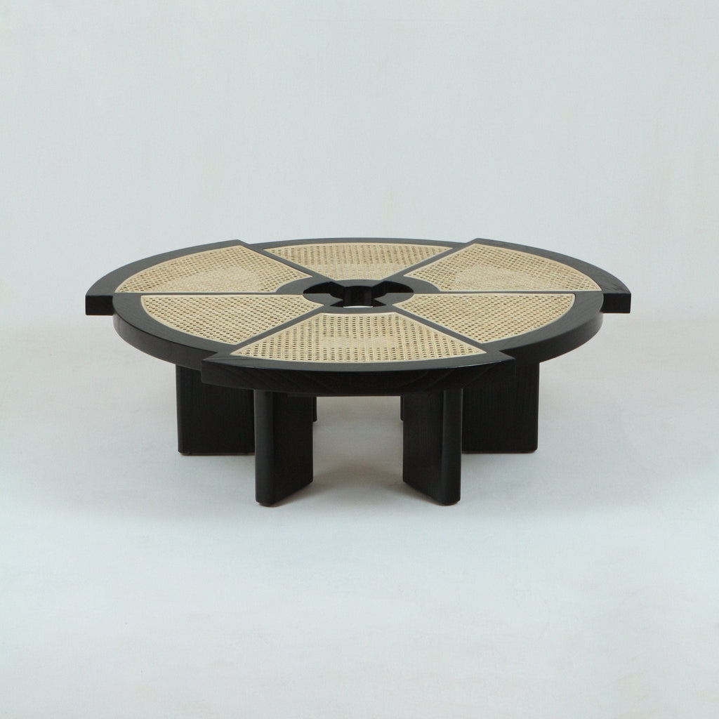 Low round coffee table in natural oak with woven cane inset divided into six radial panels, thick circular frame and short chunky pedestal legs, shown on a plain white background.