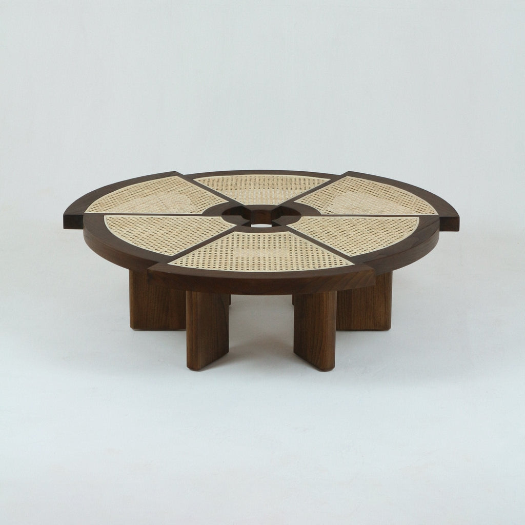 Low round natural oak coffee table with segmented woven cane top, circular center opening and chunky solid-wood base supported by short vertical legs, modern mid-century minimalist design.