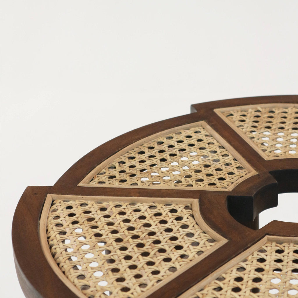 Close-up of a teak brown side table top showing woven natural cane panels set into a solid wood frame with a circular center opening, highlighting mid-century modern rattan-inset detailing.
