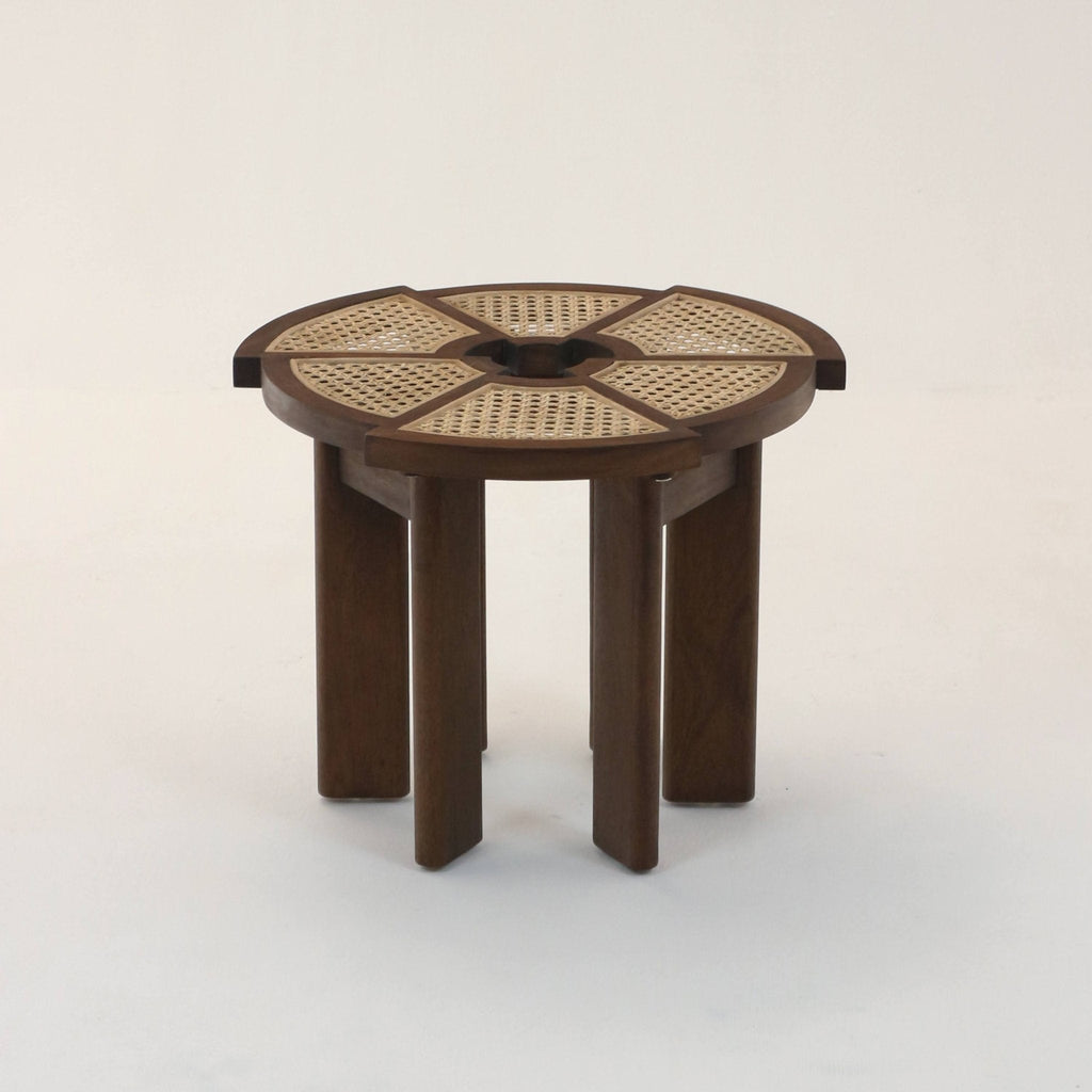 Round medium-brown teak side table with six cane-woven panels radiating from a central circular opening, supported by six solid rectangular legs for a minimalist mid-century modern look.