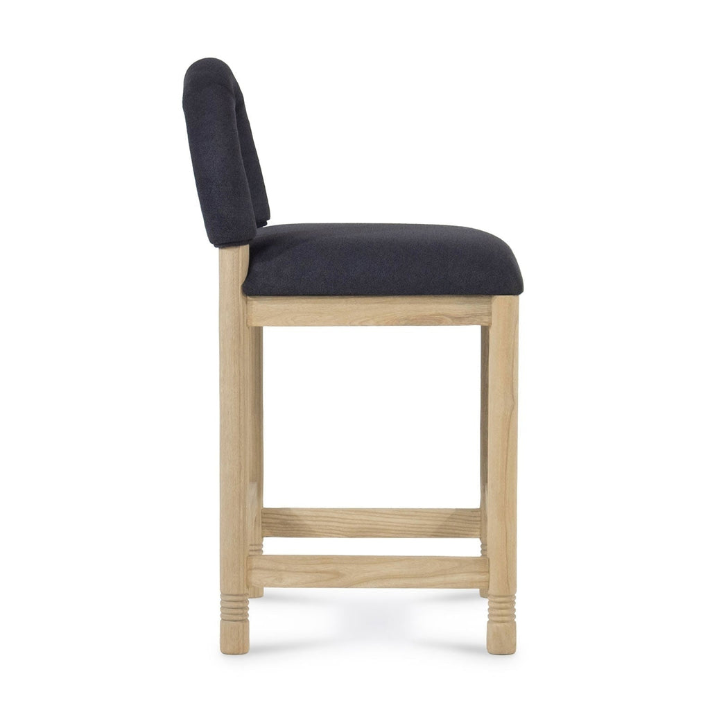 Side profile of a counter stool with a natural oak frame and charcoal bouclé fabric seat and low back, showing square legs, rectangular stretchers and subtle turned detailing at the feet.