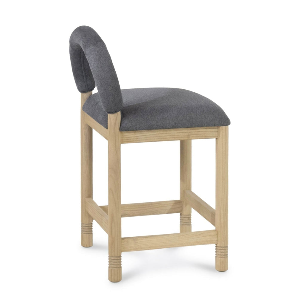 Side view of a counter-height stool with a natural oak frame and cushioned gray bouclé seat and low rounded backrest.