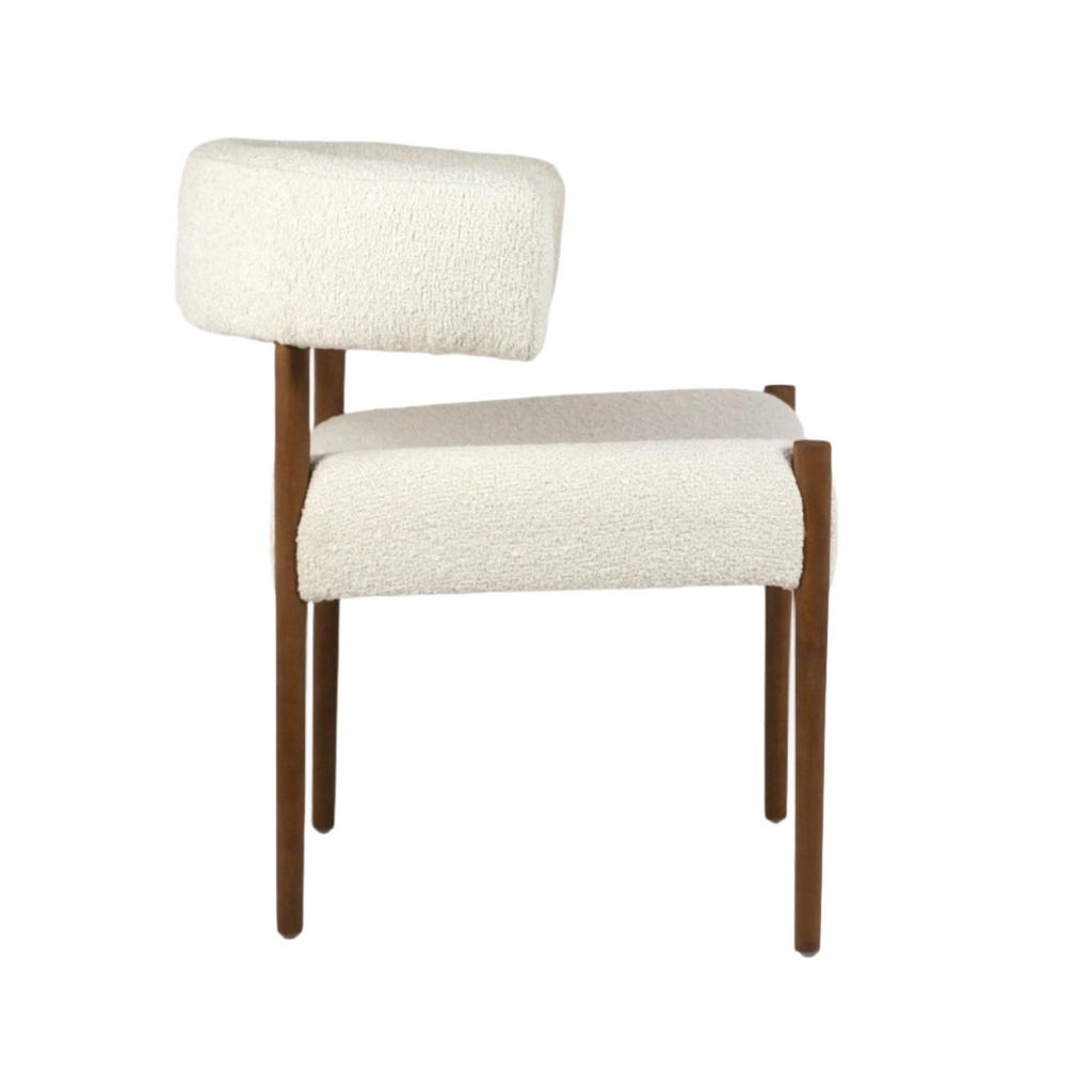 Side profile of a cream alpaca bouclé dining chair with a curved upholstered back and seat, supported by slim natural wood legs in a modern mid-century style.