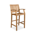 Natural teak outdoor bar stool in a coastal style with a slatted curved back, slatted seat, arched armrests and a metal-topped footrest, shown against a white background.