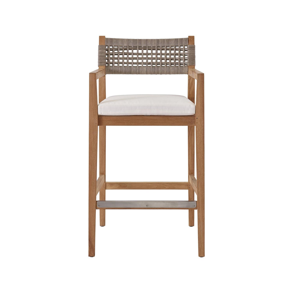 Coastal teak outdoor bar stool with a natural teak solid-wood frame, neutral woven rope back, white fabric upholstered seat cushion, armrests and a metal-reinforced footrest.