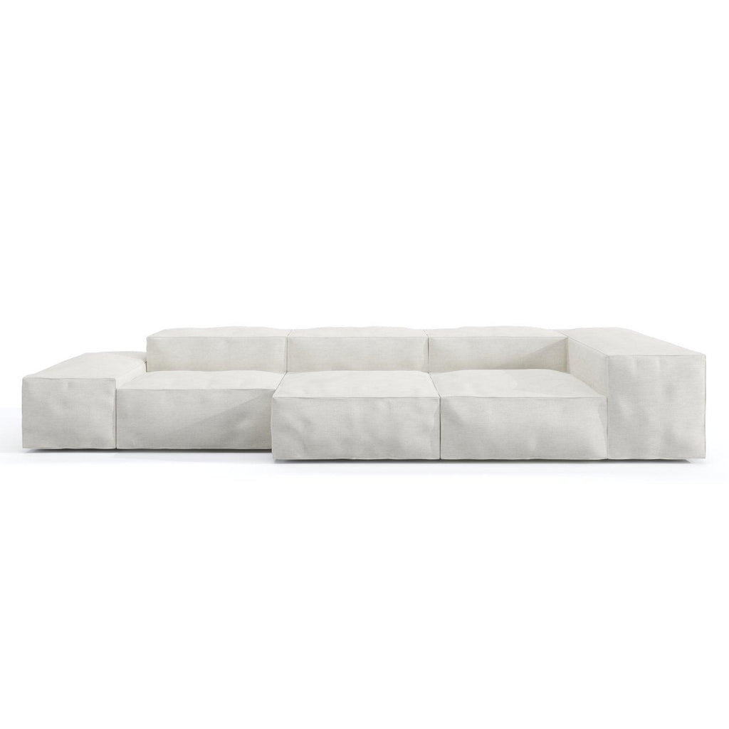 Low-profile modular sofa upholstered in loose white linen with deep cushioned block seats, wide low arms and a subtle wooden base, shown against a plain white background.