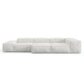 Low-profile modular sofa upholstered in loose white linen with deep cushioned block seats, wide low arms and a subtle wooden base, shown against a plain white background.