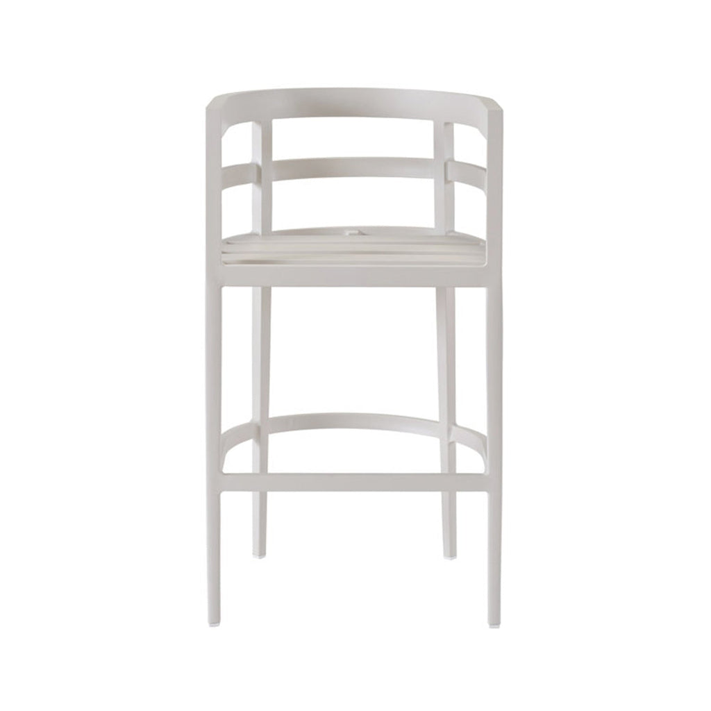 Front view of a coastal-style teak outdoor bar stool in a pale natural finish, with a slatted seat and thin upholstered cushion, curved slatted back with integrated armrests, slim tapered legs and a curved footrest.