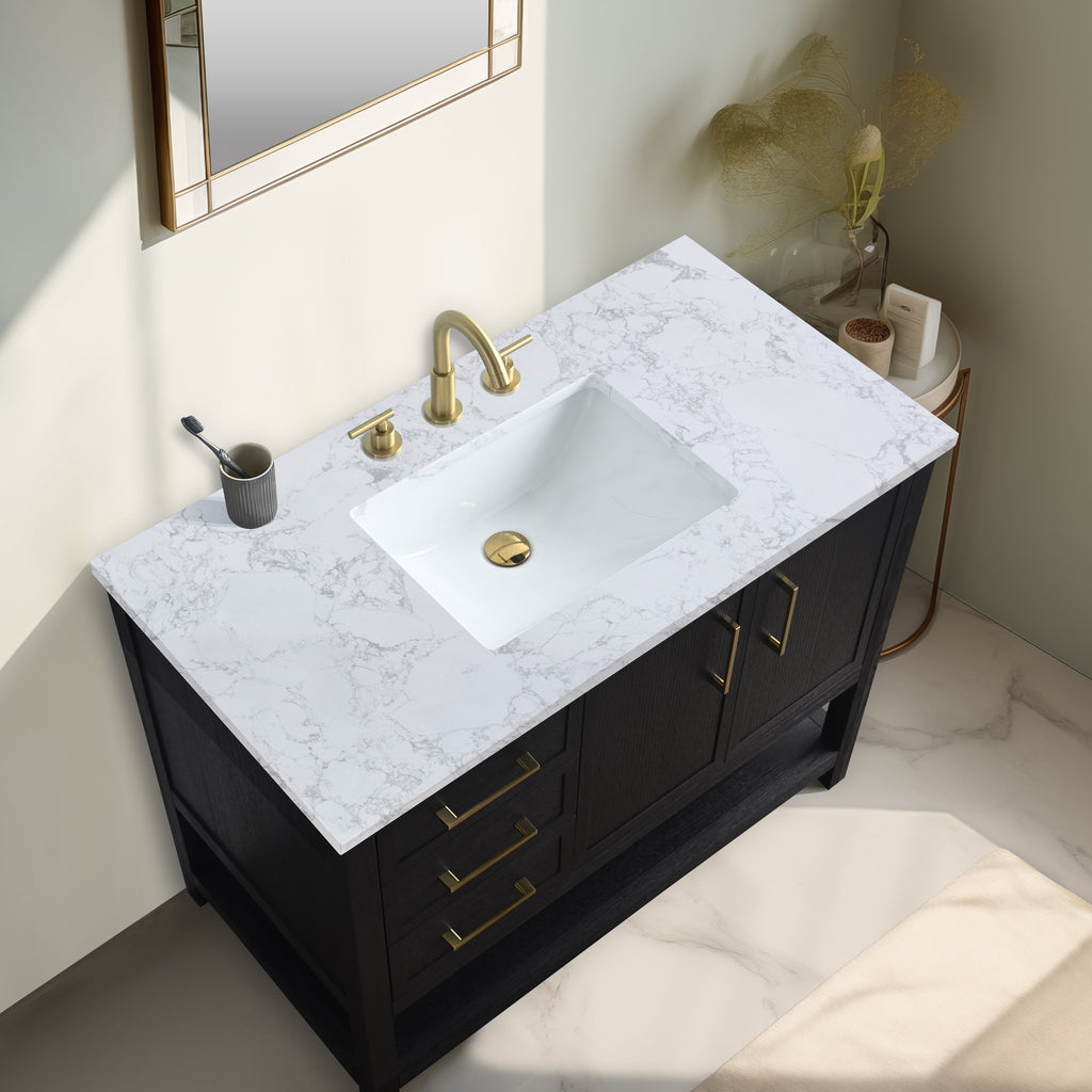 Overhead view of a freestanding black solid wood bathroom vanity with a white marble-look stone top, rectangular undermount ceramic sink, and brass faucet, handles and drain.