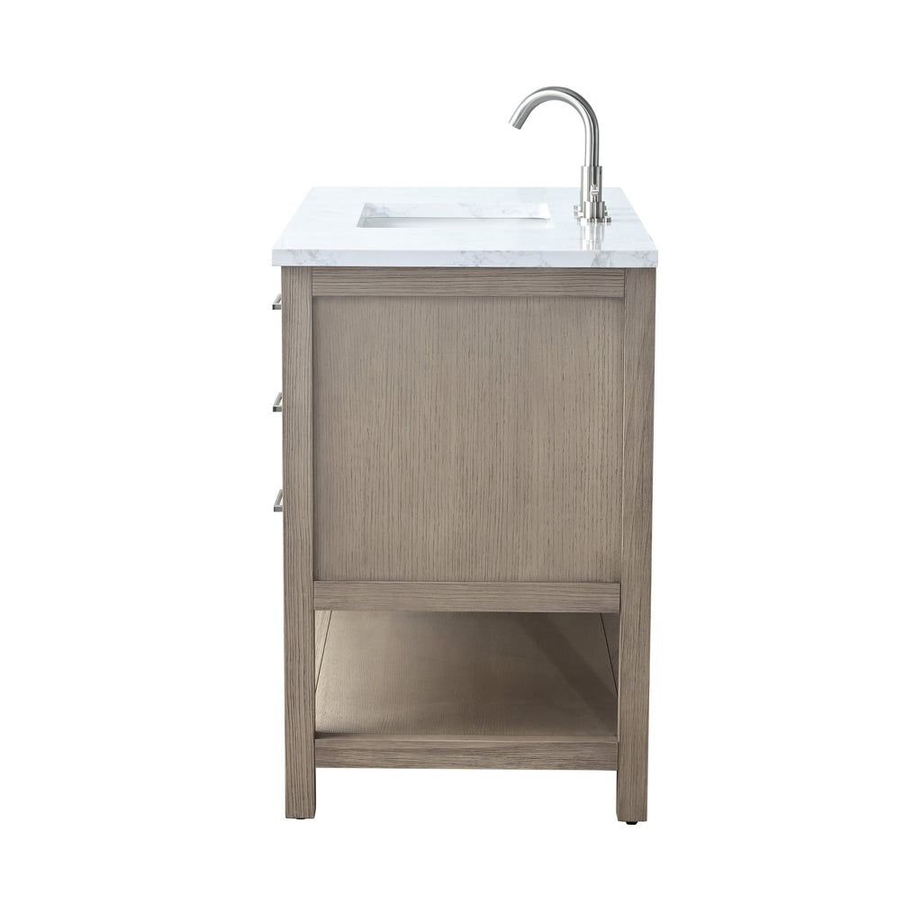 Side view of a modern single-sink bathroom vanity in a stone-colored solid wood finish with a white marble top, integrated rectangular sink, chrome gooseneck faucet, three drawer handles visible and an open lower shelf.